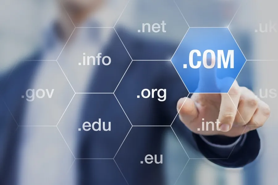 Businessman selecting .com domain among various top-level domains displayed in hexagonal shapes on digital interface