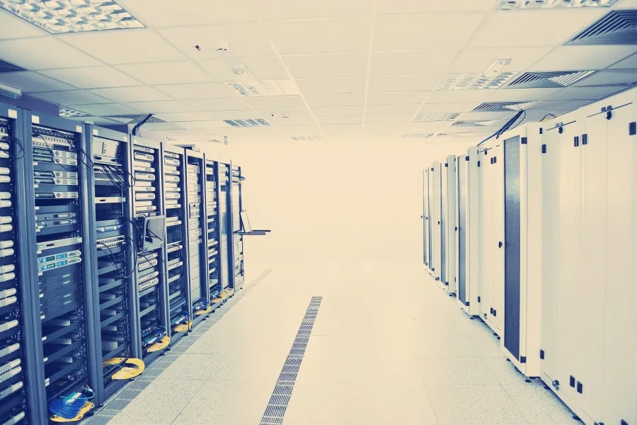 Centru de date modern cu servere și echipamente IT organizate în rânduri, iluminat cu plafon suspendat.